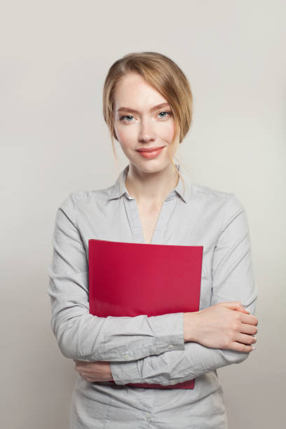 Friendly successful woman with documents standing against white background Friendly successful woman with documents standing against white background dissertation photos stock pictures, royalty-free photos & images