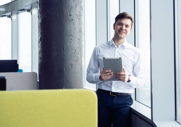 istock Happy young man smiling into the camera with a tablet in his hand. 1213163889