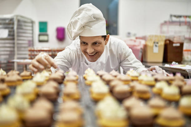 istock Smiling Chef Decorating Cupcakes in Commercial Kitchen 1213165132
