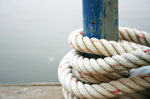 Coarse rope wrapped around wooden pole with blur background.