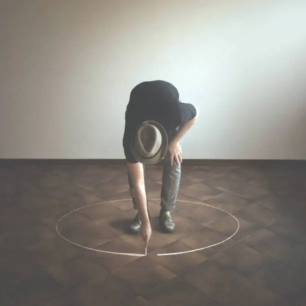 Photo of man drawing white circle  around him with chalk, abstract concept