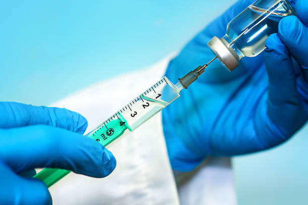 vacina em uma garrafa com uma seringa em um fundo azul. o conceito de medicina, saúde e ciência - injeção insulina luva - fotografias e filmes do acervo