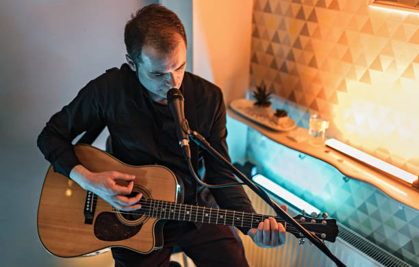 istock Man playing acoustic guitar and singing on stage 1213175221