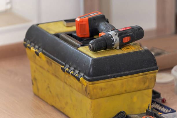 istock Electric hand tools, the old drill lies on a dusty yellow tool box 1213178589