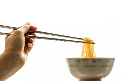Asian instant noodle with chopsticks in ceramic bowl on white background