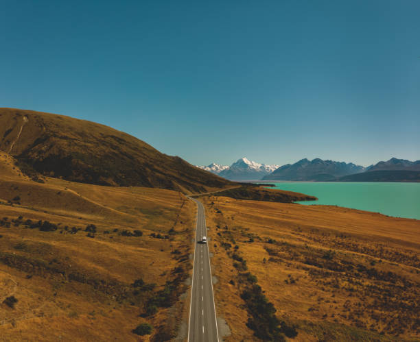 Drone aerial above highway road along vibrant lake towards iconic mountain landscape Location:  Lake Pukaki, Mount Cook National Park, South Island, New Zealand
Shot with Dji Mavic Air stitched image stock pictures, royalty-free photos & images