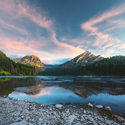 Peaceful summer view on Obersee lake in Swiss Alps. Sunrise sky and mountains reflections in clear water. Nafels village, Switzerland. Landscape photography