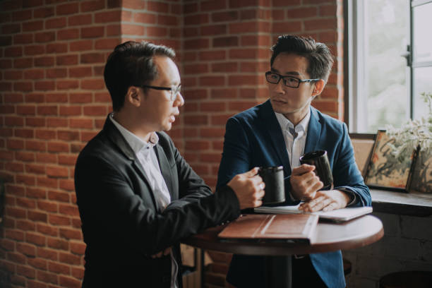 istock 2 asian chinese white collar workers having discussion during their coffee break in lounge using laptop and digital tablet 1213187038