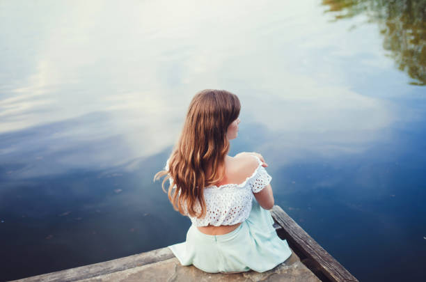 istock girl sitting by the river 1213188785