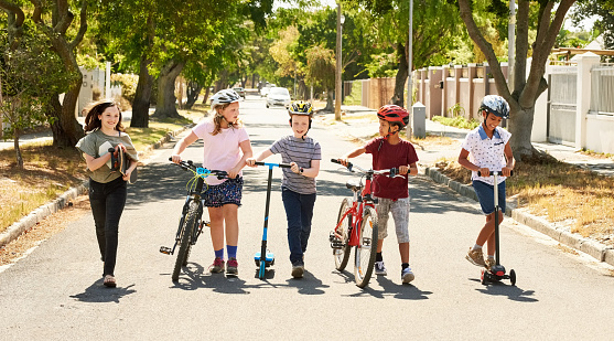 Shot of a kids playing with skateboard and scooters on the road