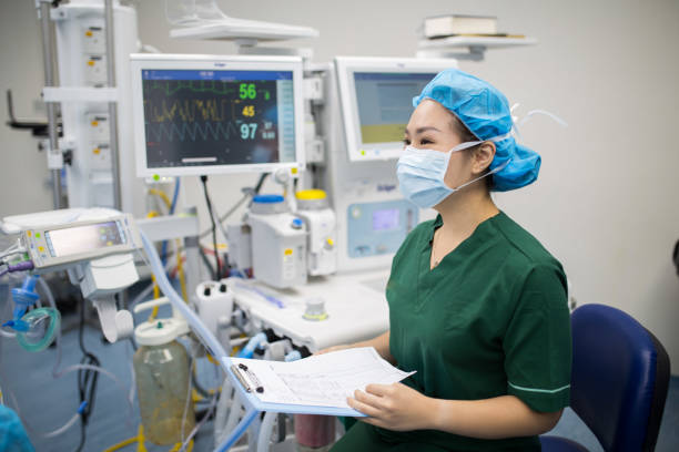Doctor is reading patient report and checking cardiogram monitor before surgery in operation room. stock photo