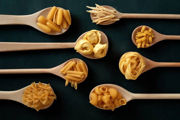 laici piatti con diversi tipi di pasta tradizionale italiana. penne, tagliatelle, fusilli, farfalle, spaghetti e altri. concetto tradizionale italiano di cusine - italian cuisine dry pasta directly above foto e immagini stock