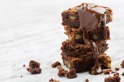 Classic dark chocolate brownie tower with nuts and melted chocolate.