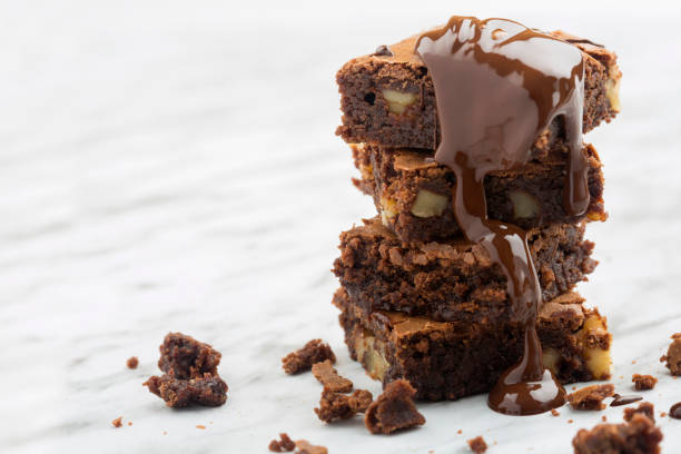 шоколадная пирожная башня с орехами и расплавленным шоколадом. - brownie baked bakery brown стоковые фото и изображения