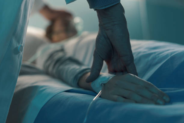 Doctor assisting a young patient at the hospital Doctor assisting a young patient at the hospital and taking pulse, she is lying on the bed and sleeping night hospital bed stock pictures, royalty-free photos & images