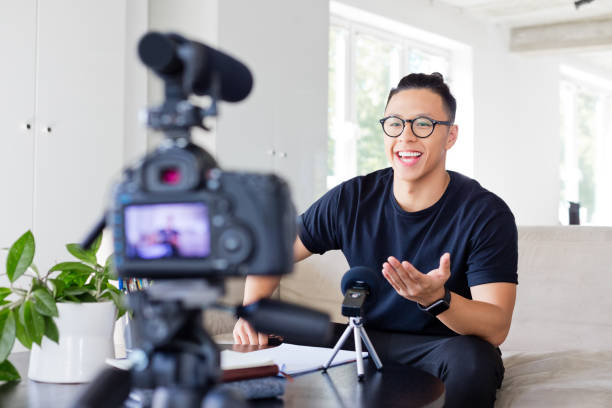 Friendly young man vlogging Handsome asian young man making a video blog. Male vlogger recording content on digital camera. influencer stock pictures, royalty-free photos & images