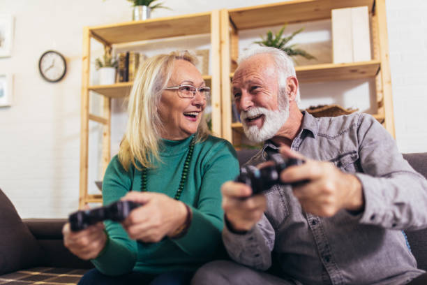 istock Senior couple having fun at home playing video game holding joysticks in hands. 1213201535