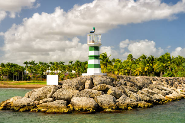 istock lighthouse on stones near water and palm trees 1213202324