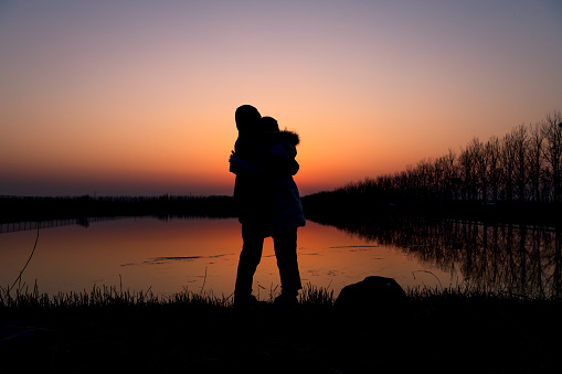 The couple hugged each other by the lake at sunset