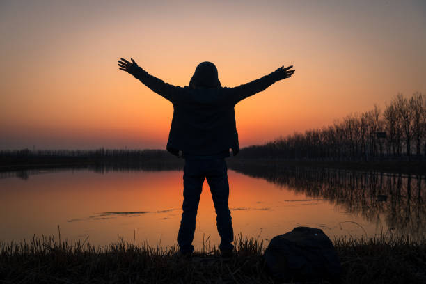 istock Hiker with arms up by the lake at sunset 1213203530
