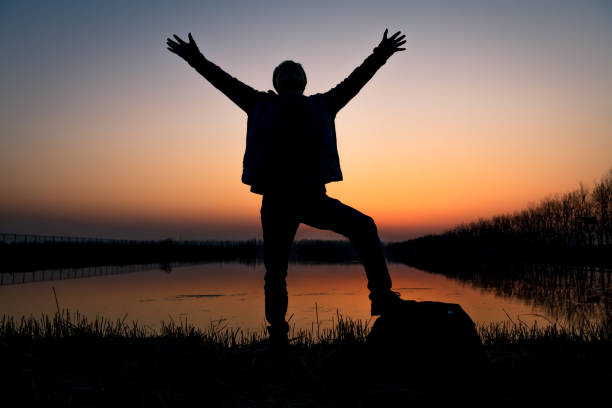 istock Hiker with arms up by the lake at sunset 1213204463