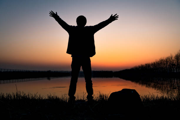 istock Hiker with arms up by the lake at sunset 1213204626