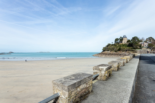 Dinard beach that faces the city.\nThis is the beach of L'écluse.\nThe tide is low and the weather is sunny.\nThe photo was taken from the Allied Promenade.\nIn the distance is a residential area that dominates the sea.\nIn the distance on the left we can see the Fort of Harbour
