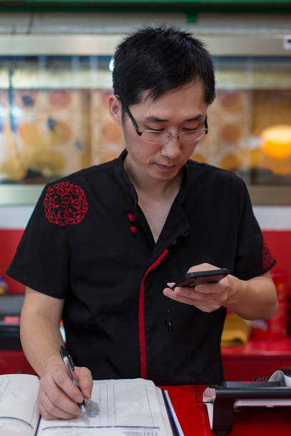 istock Chinese man watching cell phone inside Asian restaurant. 1213207473