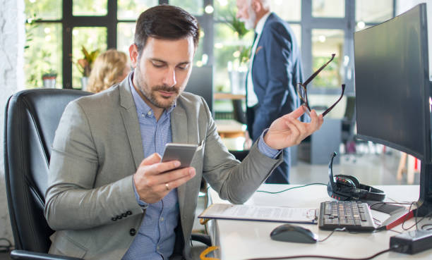 istock Handsome businessman using phone at his workplace in the office 1213207963