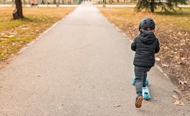 istock Small boy riding on the scooter in the park 1213209761