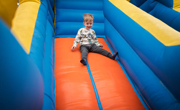 istock Happy little boy sliding down on a bouncy castle 1213209996