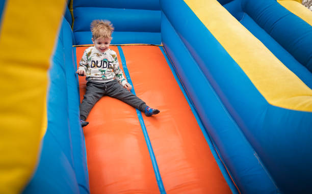 istock Happy little boy sliding down on a bouncy castle 1213210028