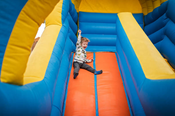 Happy little boy sliding down on a bouncy castle