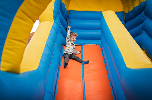 Boy sliding down on a bouncy castle Happy little boy sliding down on a bouncy castle foam rubber stock pictures, royalty-free photos & images