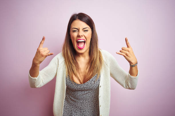 istock Young beautiful woman standing over pink isolated background shouting with crazy expression doing rock symbol with hands up. Music star. Heavy music concept. 1213212461