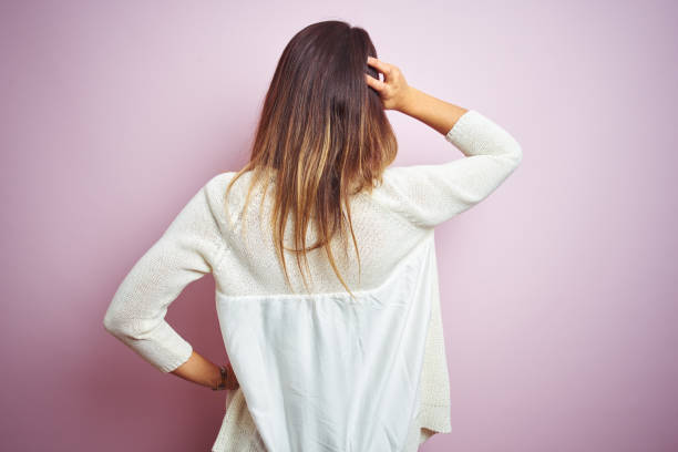 istock Young beautiful woman standing over pink isolated background Backwards thinking about doubt with hand on head 1213214139
