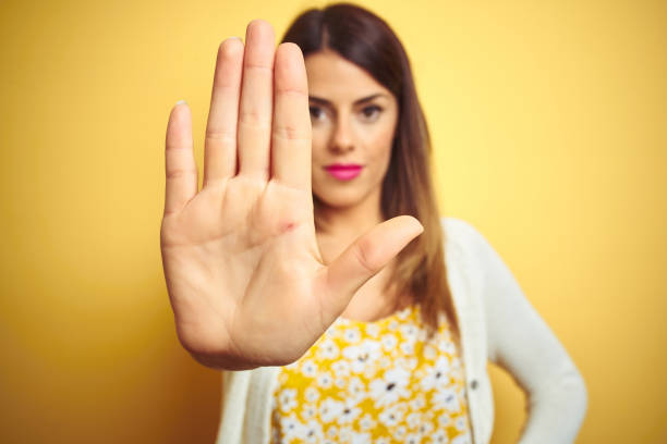 istock Young beautiful woman wearing jacket standing over yellow isolated background doing stop sing with palm of the hand. Warning expression with negative and serious gesture on the face. 1213214584
