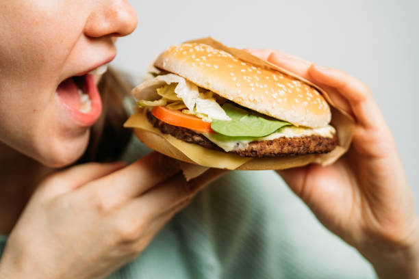 istock The girl holds a hamburger with her hands and eats it with appetite. 1213218021