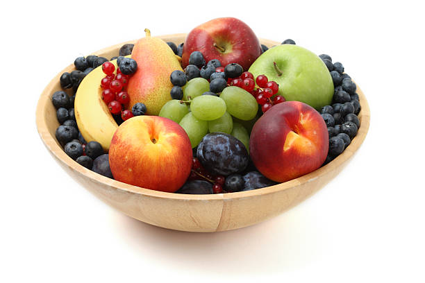 Ripe fruits on a transparent plate on a wooden background. Healthy eating.