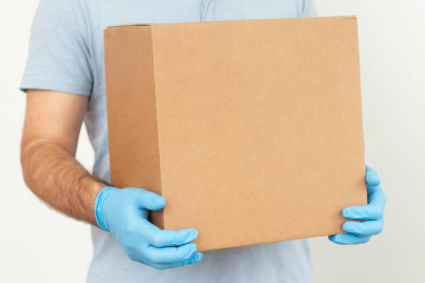 Delivery man holding cardboard boxes. Epidemic. Quarantine. copy space. Delivery by courier in medical rubber gloves. The shipping time during coronavirus
