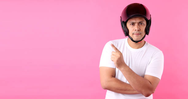 istock Asian man wearing a helmet motor and Pointing finger on empty space.on pink background in studio With copy space. 1213220761