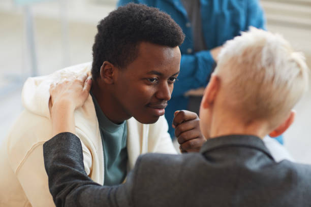 African Young Man in Support Group High angle view at young African-American man smiling gratefully to psychologist while while in support group circle, copy space consoling stock pictures, royalty-free photos & images
