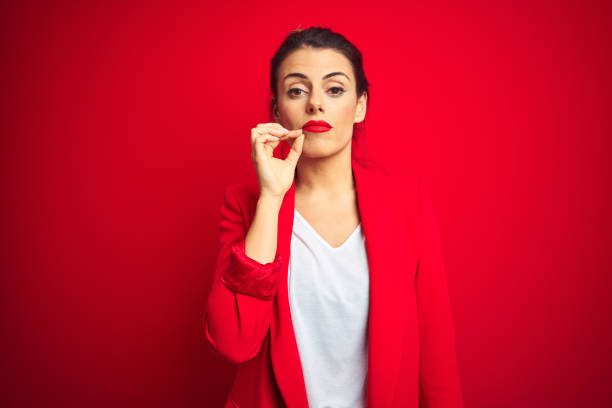 young beautiful business woman standing over red isolated background mouth and lips shut as zip with fingers. secret and silent, taboo talking - silence finger on lips businesswoman one person imagens e fotografias de stock