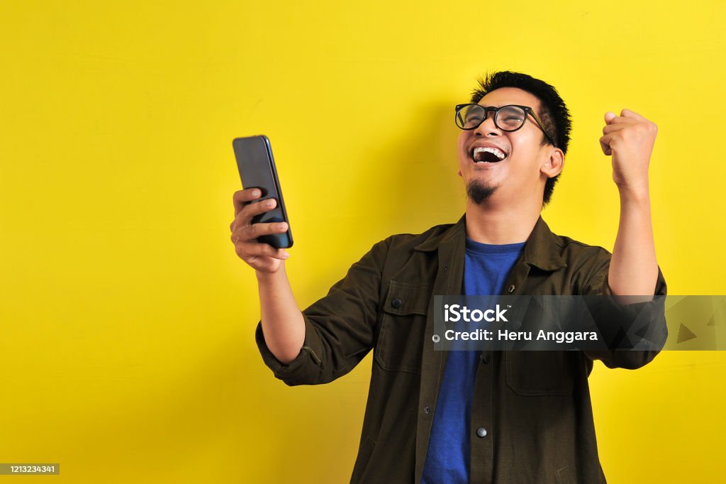Asiatischer Mann hält Smartphone mit Gewinnen Geste - Lizenzfrei Männer Stock-Foto