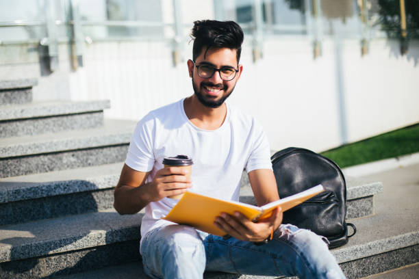 istock Handsome young manager make notice on notebook while sitting outdoors on the stairs. 1213234477
