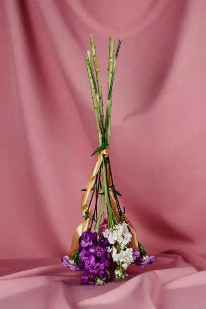 Photo of Closeup of a flower bouquet standing upside down on a table covered with pink cloth,