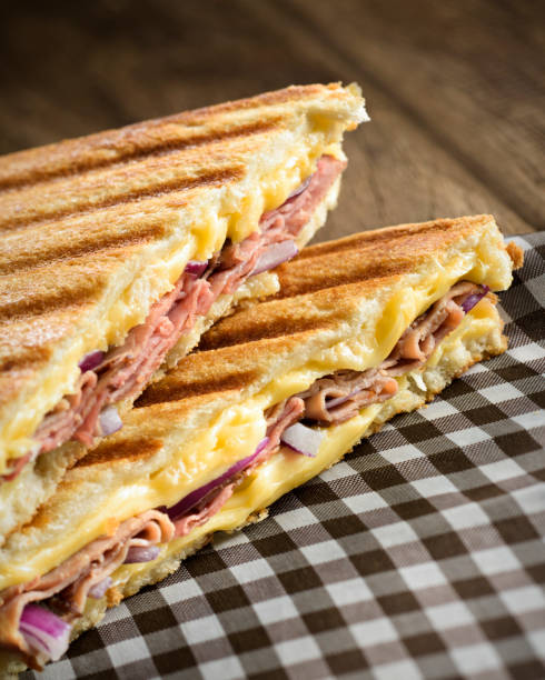 Ham and cheese sandwich Ham and cheese sandwich on a checkered napkin, with melted cheese, ham and onion, on a toasted sliced bread. ham and cheese sandwich stock pictures, royalty-free photos & images
