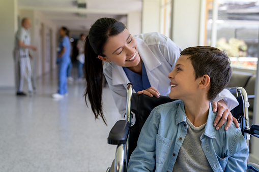 Doctor greeting a young patient in a wheelchair at the hospital