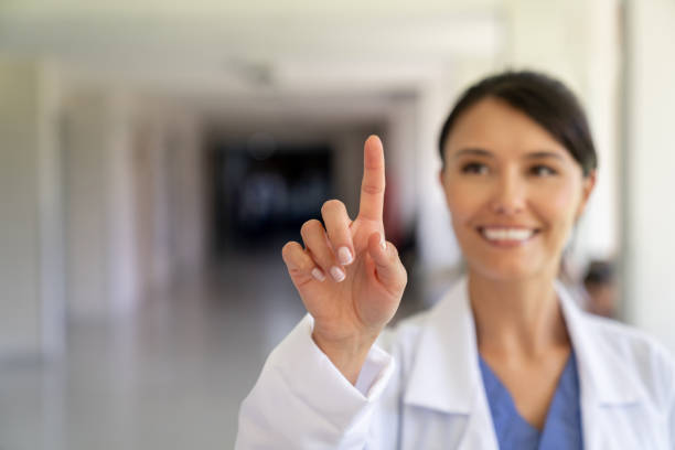 Portrait of a happy female doctor pointing at an imaginary screen at the hospital