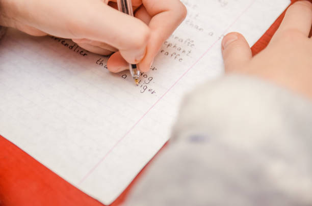istock girl does a task in English, writes in a notebook close-up 1213241563